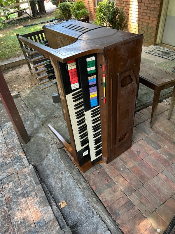 Old organ staged outside for pickup